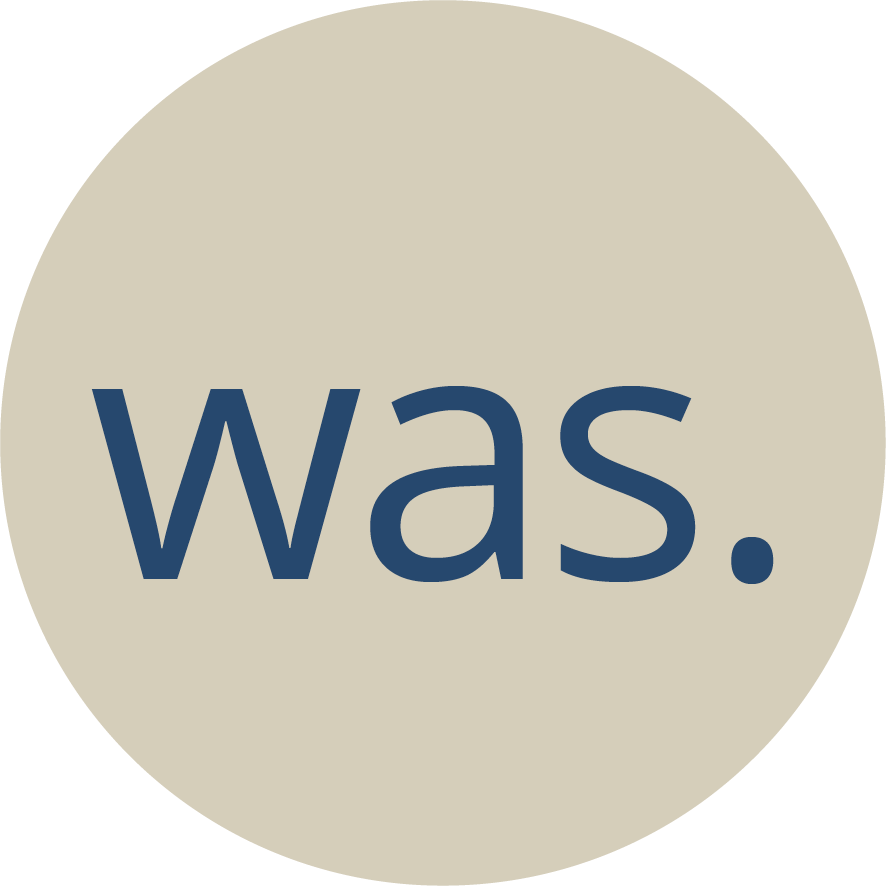 Ein weisser Kreis in dem das Wort "was" steht, das Element dient zur Navigation auf der Webseite.